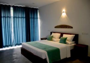 a bedroom with a large bed with green and white pillows at N 34 in Mirissa