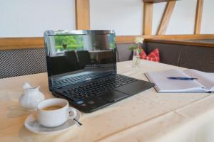 un ordinateur portable assis sur une table avec une tasse de café dans l'établissement Pension Himmelreich, à Glatt