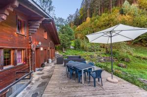 een patio met een tafel en stoelen en een parasol bij Charming Little Chalet for 6 People & Free Ski Lockers in Grindelwald