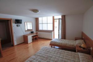 una camera d'albergo con 2 letti e una scrivania di Appartamenti Carano Al Bait ad Andalo