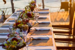 a long table with wine glasses and flowers on it at Water Blow Huts in Nusa Lembongan