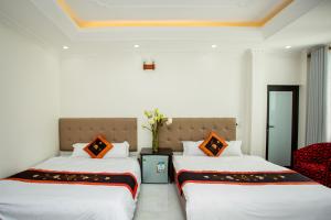 Cette chambre comprend 2 lits dans une chambre dotée de murs blancs et d'oreillers orange. dans l'établissement Van Hoa Hotel Ninh Binh, à Ninh Binh