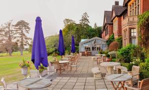 a patio with tables and chairs and umbrellas at Stanhill Court Hotel, a member of Radisson Individuals in Horley