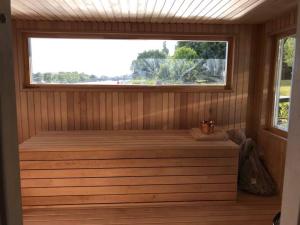 uma sauna com uma grande janela num quarto de madeira em Houseboat on the water em Liepāja