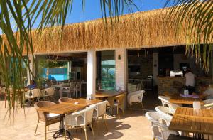 a restaurant with wooden tables and chairs and a straw roof at Zest Exclusive Hotel & Spa in Ortakent