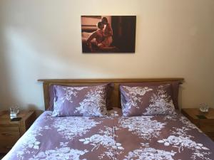 una cama con sábanas moradas y una pintura en la pared en The Bungalow, en Billericay