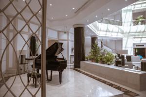 a grand piano in a lobby with a dining room at AZIMUT Grand Hotel Tashkent in Tashkent +64 photos