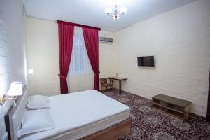 um quarto com uma cama, uma mesa e uma televisão em Orient Palace em Tashkent