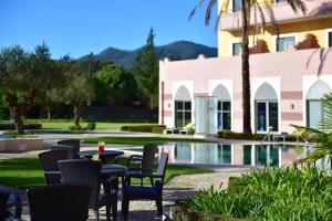 a patio with tables and chairs next to a pool at Pestana Sintra Golf Resort & SPA Hotel in Sintra