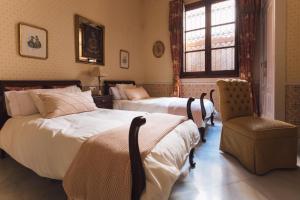 a bedroom with two beds and a chair and a window at Las Casas de Doña Concha Mezquita in Córdoba