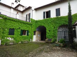 an ivycovered building with a gate and a courtyard at Villa Negri Arnoldi alla Bianca in Campello sul Clitunno