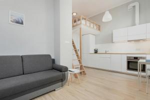 a living room with a couch and a kitchen at Apartments Poznań MTP by Renters in Poznań