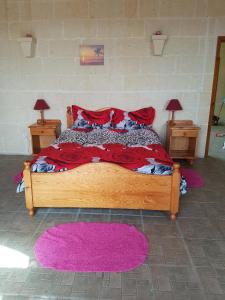 a bedroom with a large wooden bed with red pillows at Ta' Karkar Villa Bed and Breakfast in Xagħra