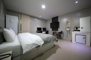 a bedroom with a white bed and a desk at Xian Hotel in Cheongju