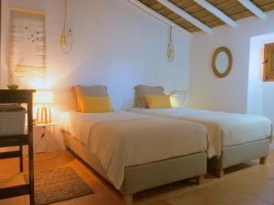 two beds in a white room with yellow pillows at Monte do Alentejo | Cozy Cottage in Redondo