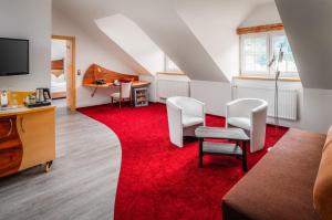 a living room with a red carpet and white chairs at Hotel Passauer Wolf in Passau