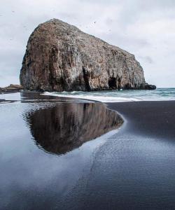 un reflejo de una roca en el agua en una playa en Cabañas Quillay, en Constitución