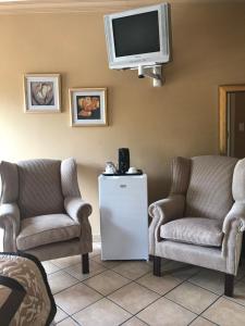 a living room with two chairs and a tv at Platinum Lodge Polokwane in Polokwane