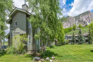a house with a yard with trees and a mountain at Mountain Jewel in Crested Butte