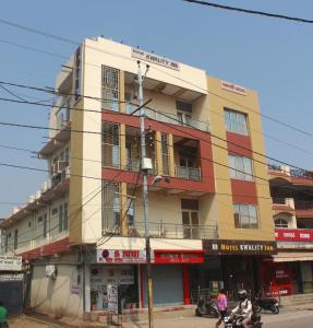 een gebouw op de hoek van een straat met mensen op motorfietsen bij Hotel Kwality Inn in Satna