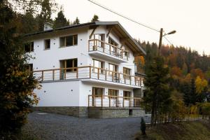a white house with wooden balconies and trees at Willa Marko z sauną, grillowiskiem i rowerownią - Dream Apart in Szczyrk