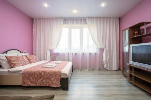 クラスノヤルスクにあるFive Stars Ray of Lightのピンクの壁のベッドルーム、ベッド1台、テレビが備わります。