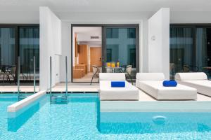 a living room with a pool with white furniture at Lindos Royal Resort in Líndos