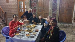 um grupo de pessoas sentadas à volta de uma mesa a comer em Umarxon em Bucara
