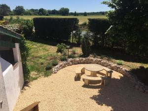 a picnic table in a garden with a stone wall at Là Grange in Parisot