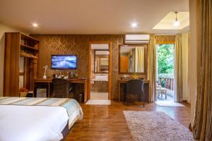 1 dormitorio con 1 cama y escritorio con TV en West Sands en Ukulhas