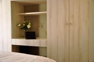 a bedroom with a shelf with a laptop and flowers at Prudentia Apartments Wilanów in Warsaw