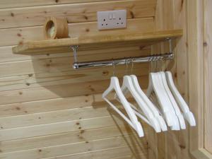 a row of white hangers on a wooden wall at Harlosh Hideaways - Aurora Pod in Harlosh