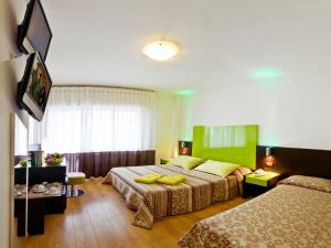 a hotel room with two beds and a flat screen tv at Hotel Concordia 3S in Bibione +11 photos