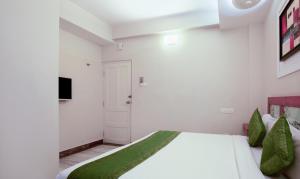 a bedroom with a large white bed with green pillows at Treebo The Qasr in Cochin