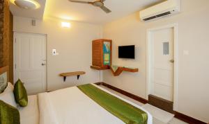 a bedroom with a bed and a flat screen tv at Treebo The Qasr in Cochin