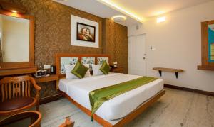 a hotel room with a bed and a desk and a mirror at Treebo The Qasr in Cochin