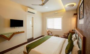 a bedroom with a bed and a flat screen tv at Treebo The Qasr in Cochin