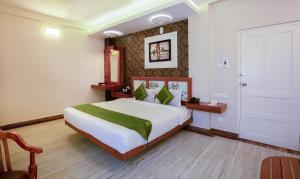a bedroom with a large white bed with green pillows at Treebo The Qasr in Cochin