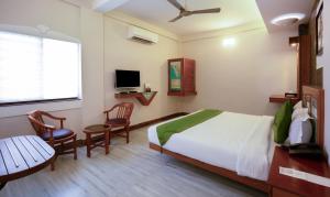 a bedroom with a bed and a table and chairs at Treebo The Qasr in Cochin