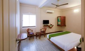 a bedroom with a bed and two chairs and a television at Treebo The Qasr in Cochin