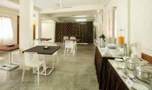 a kitchen with white chairs and a counter with a table at Treebo Trend The Qasr in Cochin