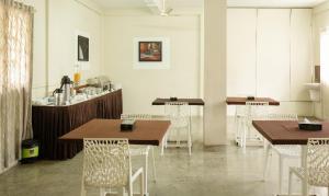 a dining room with wooden tables and white chairs at Treebo The Qasr in Cochin
