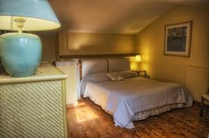 1 dormitorio con 1 cama y un jarrón azul en una encimera en Tuscania Terme Suites Apartments, en Tuscania