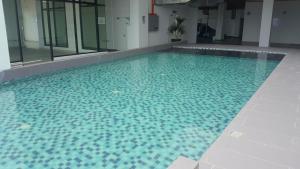 a large swimming pool with a blue tile floor and windows at Prestige Sky Riverfront in Kota Bharu