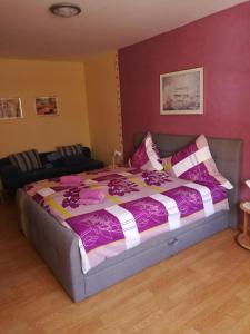 摩澤爾河畔的策爾的住宿－Fewo Winzerstrasse，一间卧室配有一张带紫色和白色棉被的床