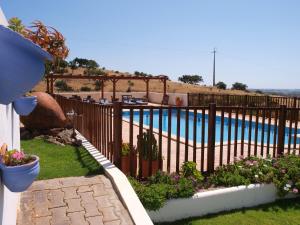 a fence next to a swimming pool with flowers at Quinta dos Medronheiros in Altura