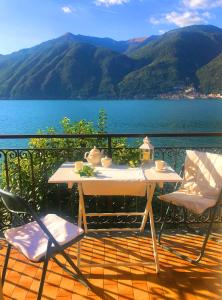 een tafel en stoelen op een balkon met uitzicht op het water bij Holidays Home Rivabella in Lezzeno