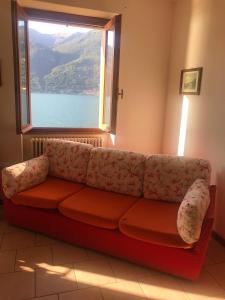 een rode bank in een kamer met een raam bij Holidays Home Rivabella in Lezzeno