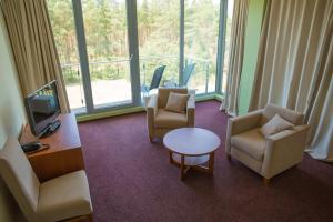 Ein Zimmer mit zwei Stühlen, einem Fernseher und einem Tisch in der Unterkunft Meduza Hotel in Palanga