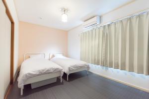 two beds in a room with a window at Kujo Ume May In Higashikujo in Kyoto